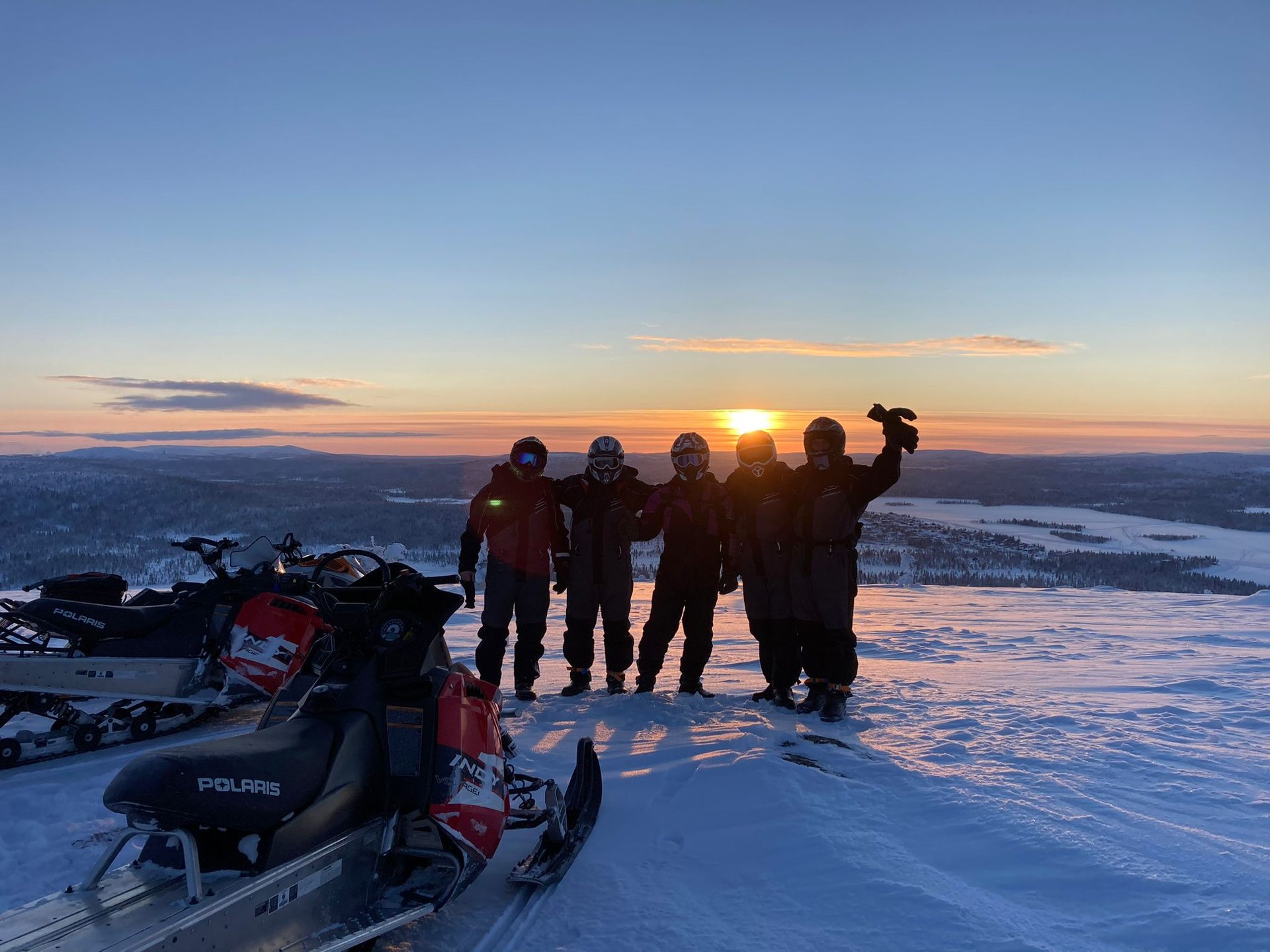 Gruppe mit Snowmobilen im Sonnenuntergang in Lappland